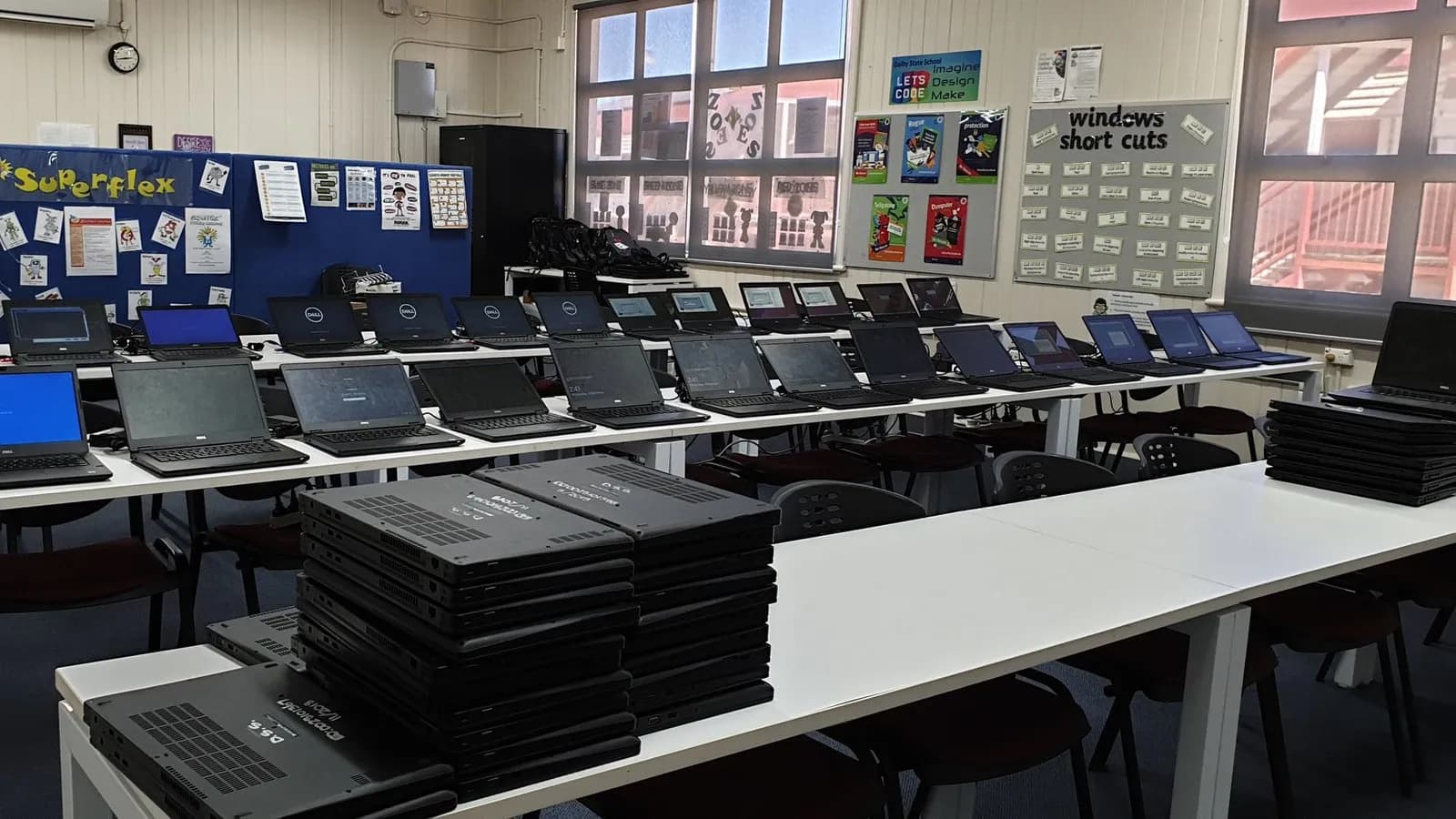 Rows of laptops on desks in an empty school computer room
