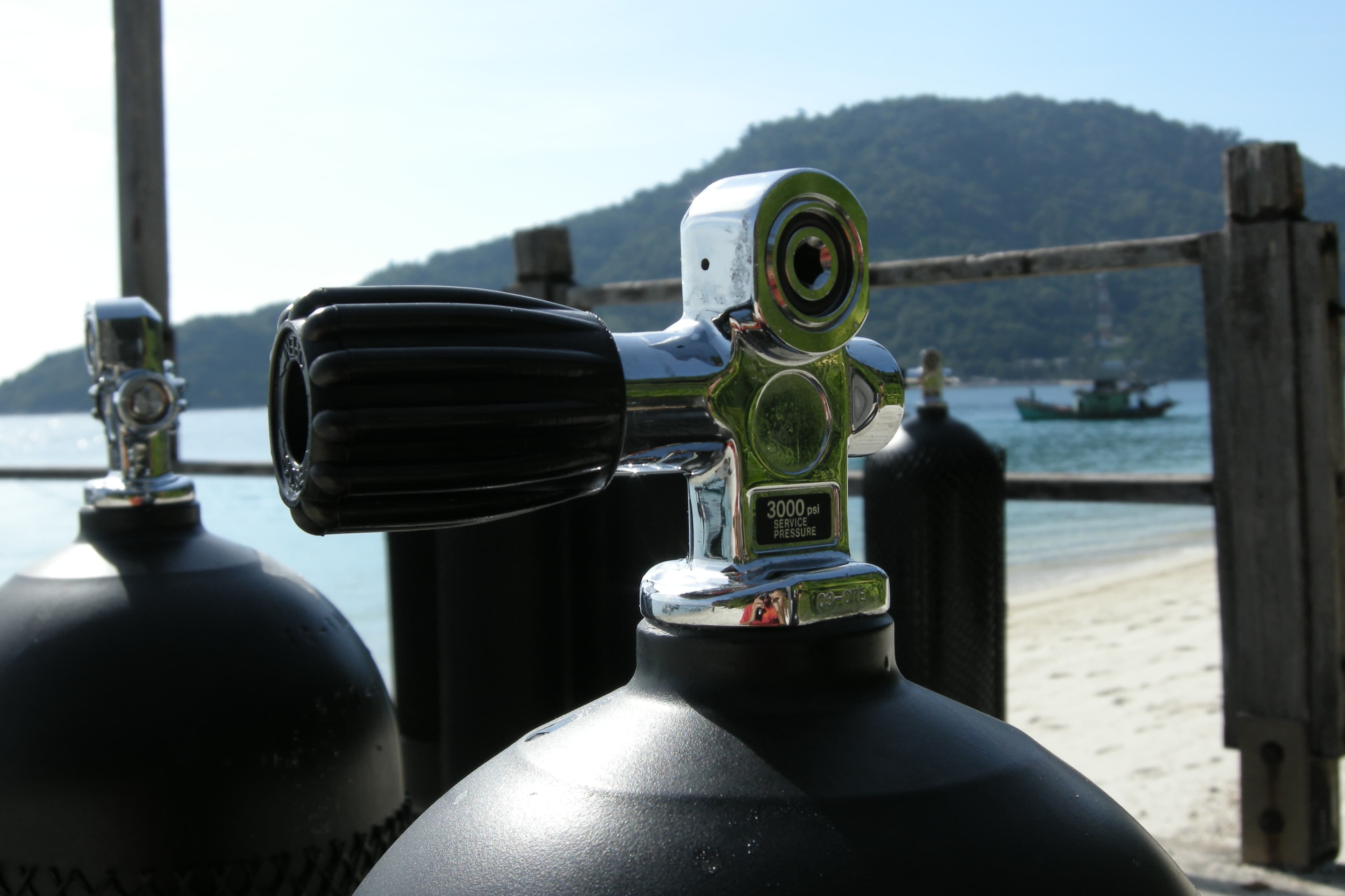 A technical diver descending through deep open water with multiple gas cylinders visible