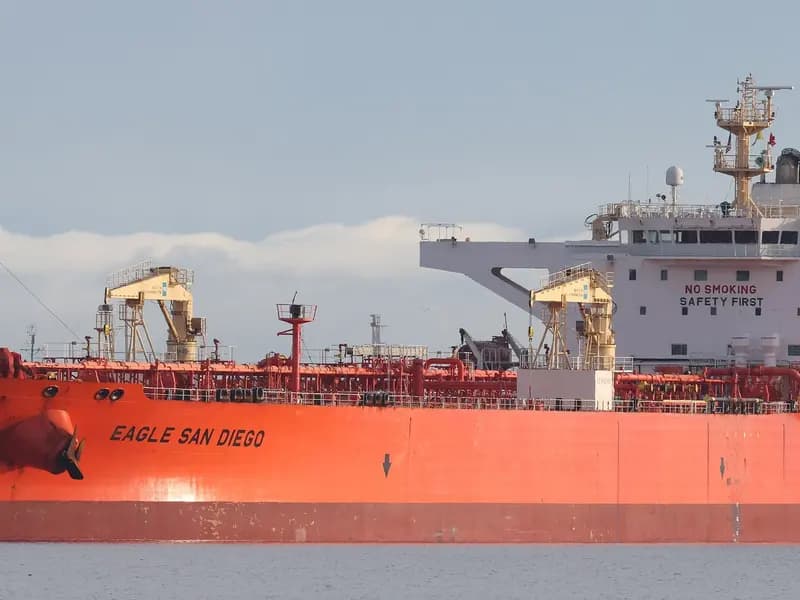 A loaded crude oil tanker alongside, its red hull low in the water and the accommodation block and bridge visible aft