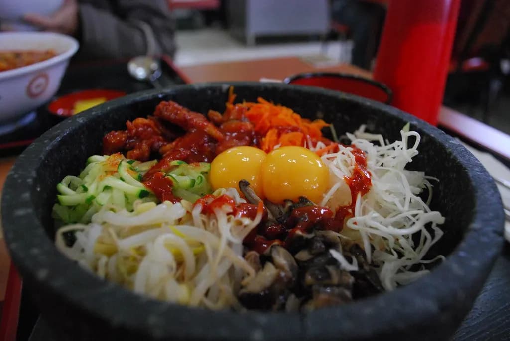 Colorful Korean bibimbap with vegetables, beef, fried egg, and gochujang sauce