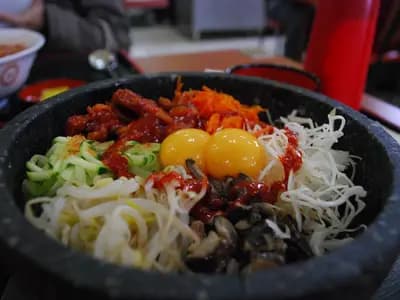 Colorful Korean bibimbap with vegetables, beef, fried egg, and gochujang sauce