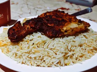 Platter of chicken machboos with golden basmati rice, tender chicken pieces, caramelized onions, and green pepper rings, traditional Gulf dish