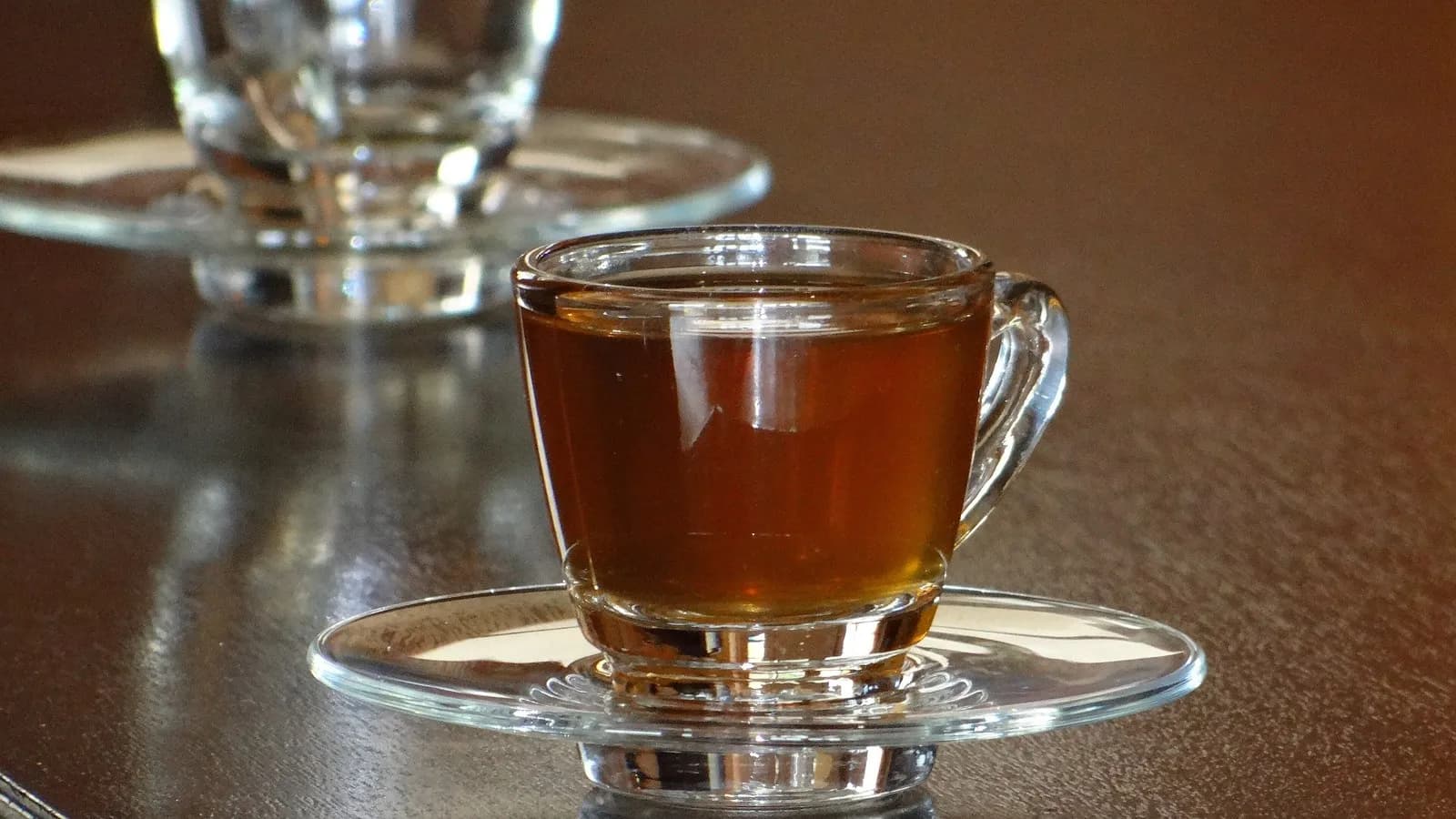 A glass cup of hot tea with honey on a wooden table