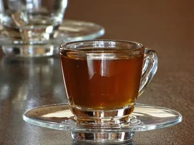 A glass cup of hot tea with honey on a wooden table