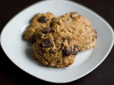 A croissant split open to reveal gooey baked chocolate chip cookie dough packed inside its flaky layers