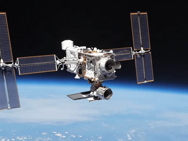 A satellite with extended solar arrays in orbit above the curve of the Earth