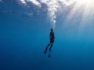 A freediver descending a guide rope into deep blue water