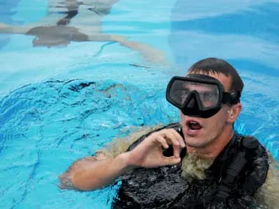 A freediver wearing a monofin descends along a guide line into deep open water