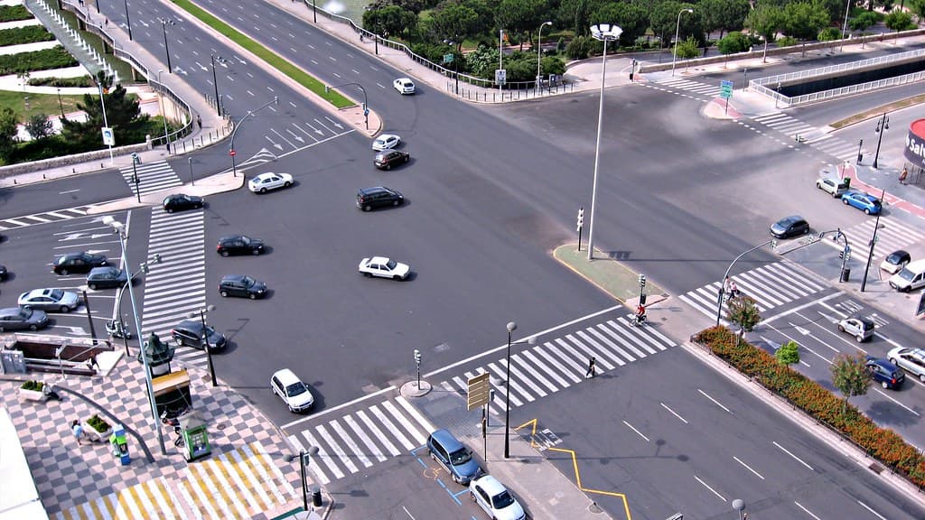 Pedestrians crossing a busy city road at a marked intersection