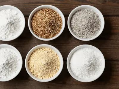 Small bowls of different gluten-free flours arranged on a wooden surface