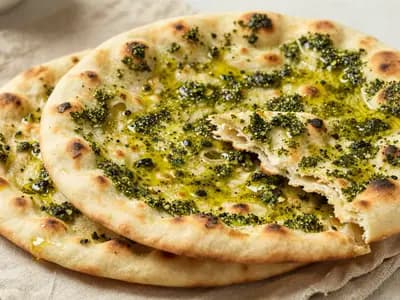 Za'atar flatbreads on a cloth, one torn to show a soft crumb