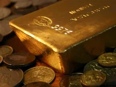 Gold bars beside a professional financial market display