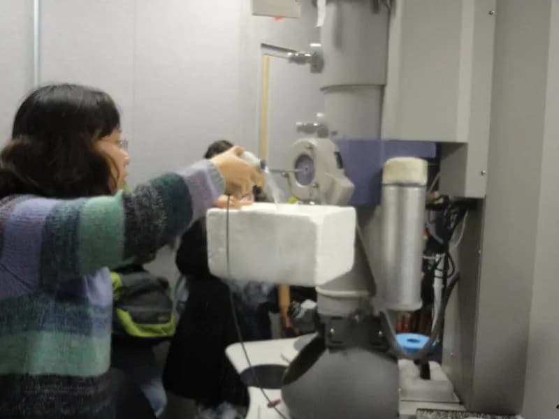 Researchers loading a sample into a cryo-electron microscope, the instrument the UC San Diego team used to image the enzyme at work