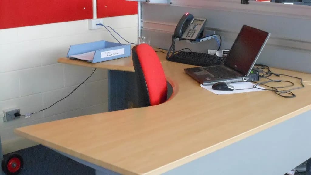 An empty office desk with a laptop and a telephone