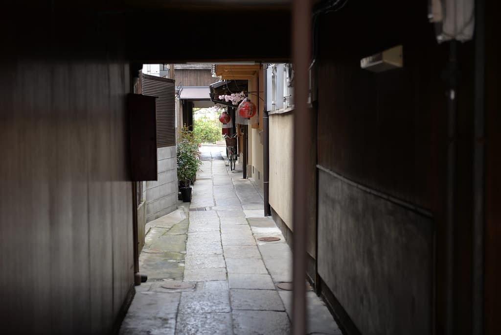 Crowds of tourists walking through a narrow historic street in Kyoto lined with traditional wooden buildings