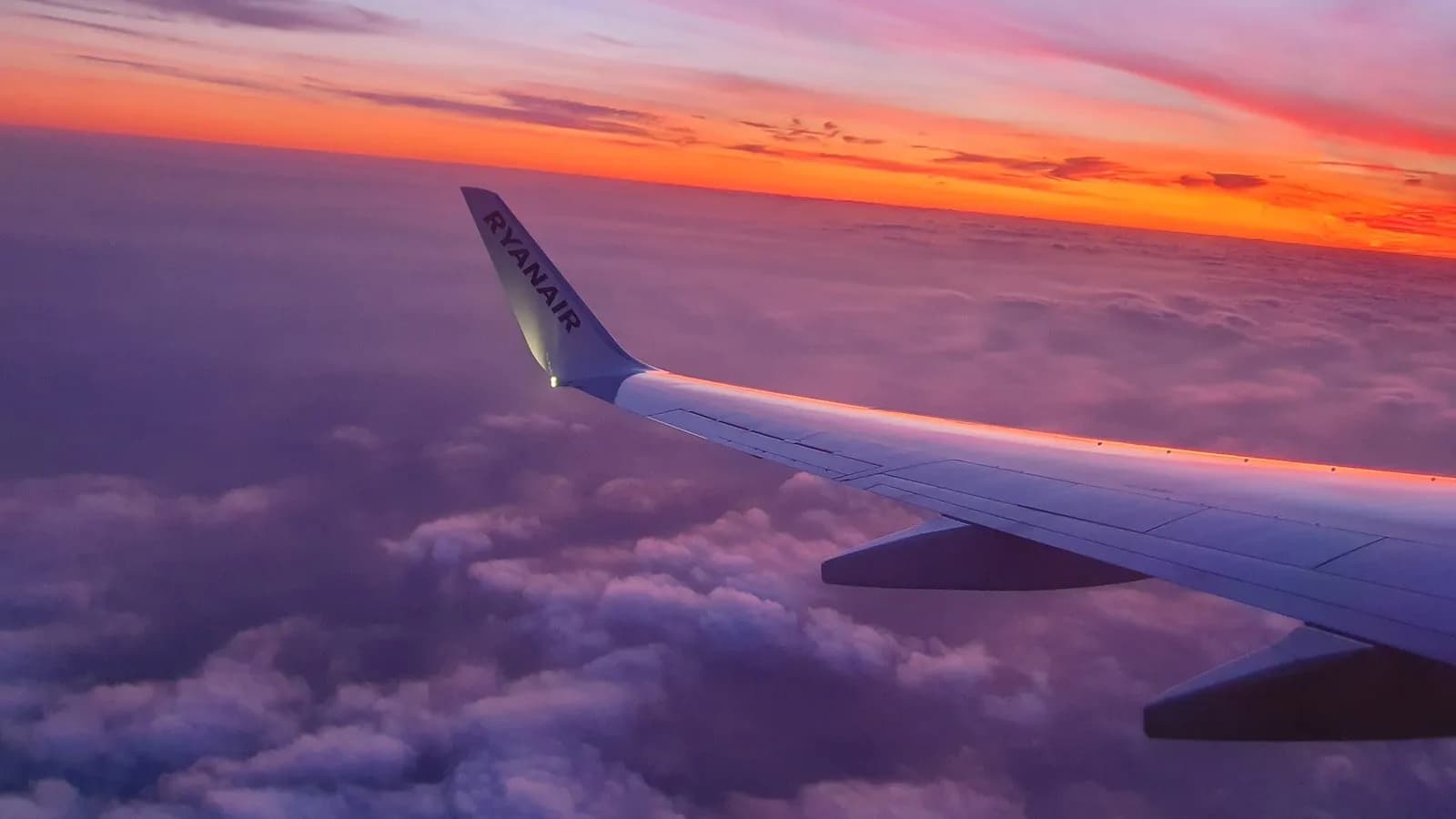 Sunrise over the wing of an airliner at cruising altitude, photographed from a window seat in 2019