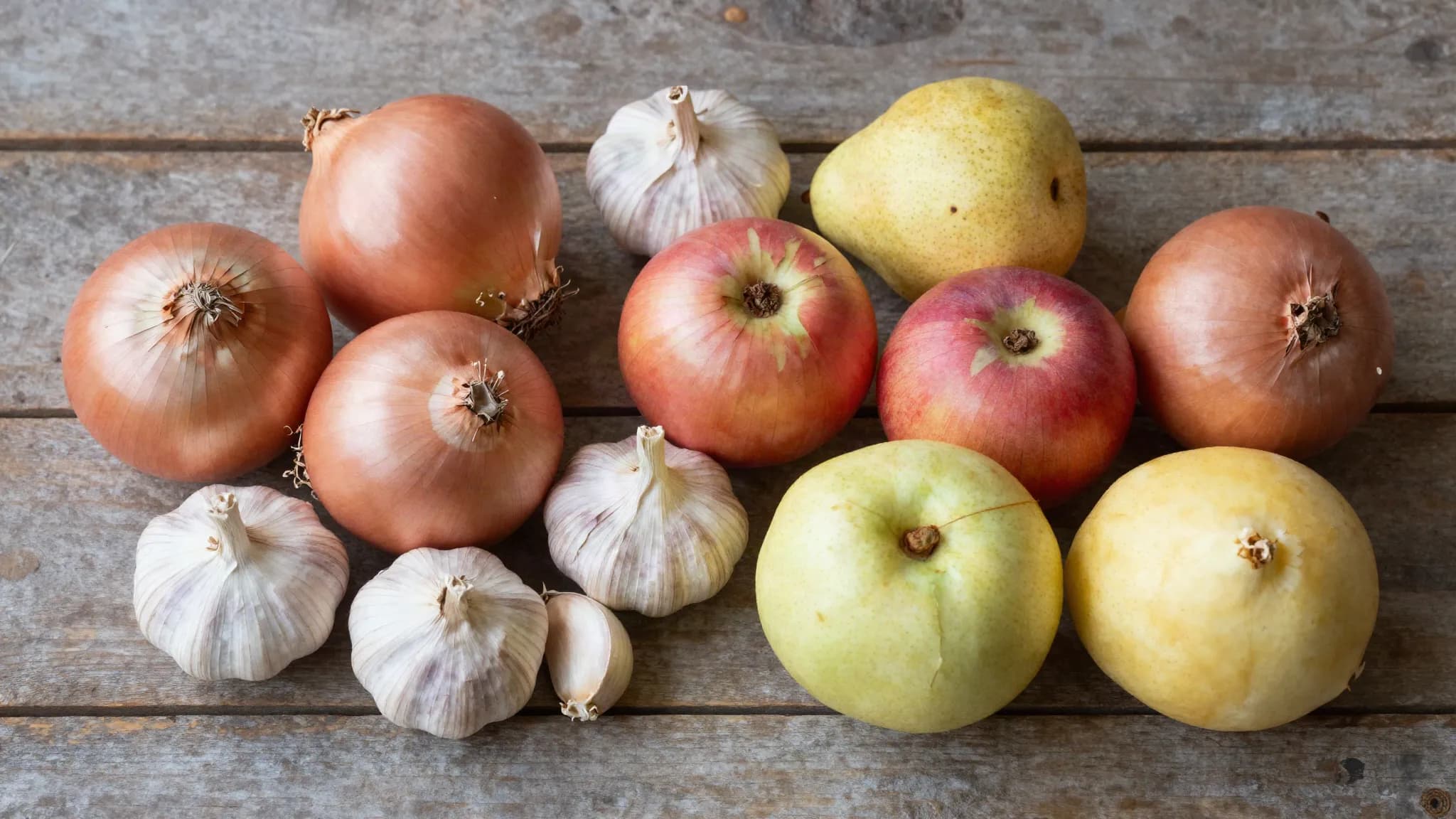 Onions, garlic, apples and pears on a wooden table