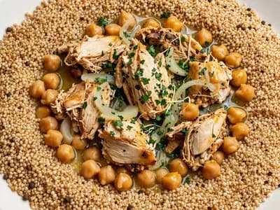 A platter of maftoul topped with chicken, chickpeas and parsley