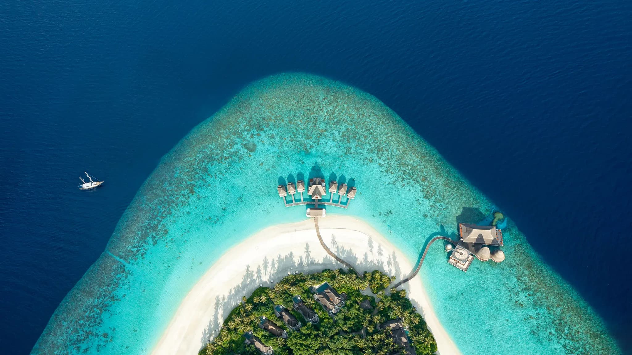 An aerial view of a Maldives atoll reef and lagoon with a dive boat anchored offshore