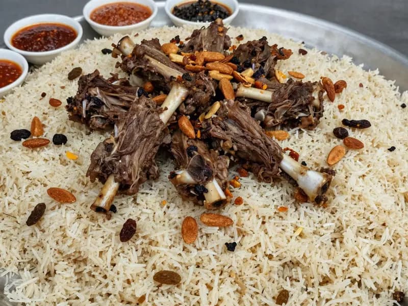 A large communal platter of spiced rice topped with slow cooked lamb and fried nuts