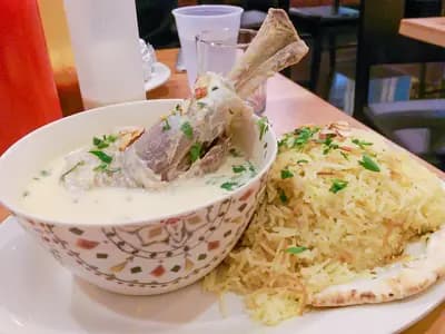 Large serving platter of mansaf with turmeric rice, tender lamb in creamy jameed yogurt sauce, toasted almonds, and fresh parsley garnish