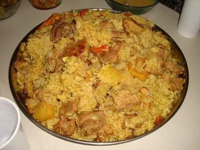 A moulded dome of spiced rice topped with aubergine and toasted nuts on a platter