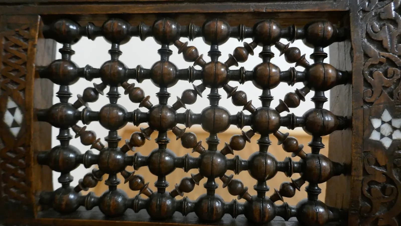 A turned wood mashrabiya screen with carved surround