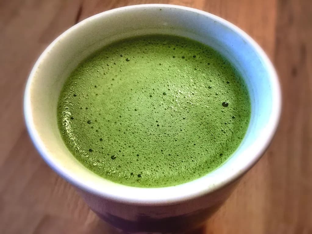 Matcha latte with decorative foam art served in minimalist cafe setting