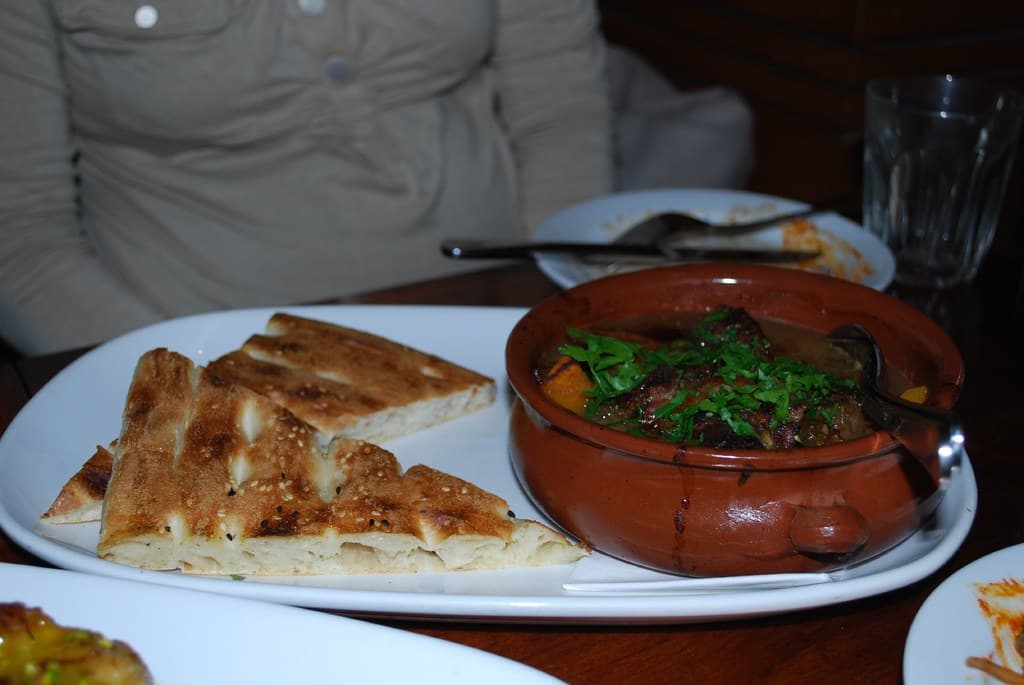 Traditional Moroccan chicken tagine with tender chicken, preserved lemon, green olives, and aromatic spices served over fluffy couscous