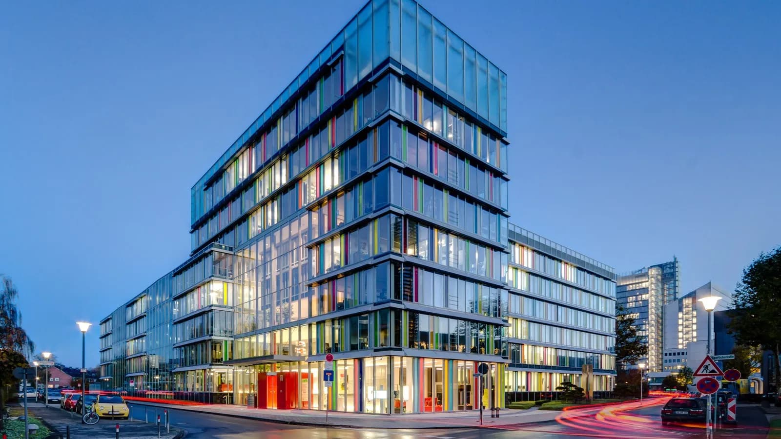 A modern glass office building lit at dusk