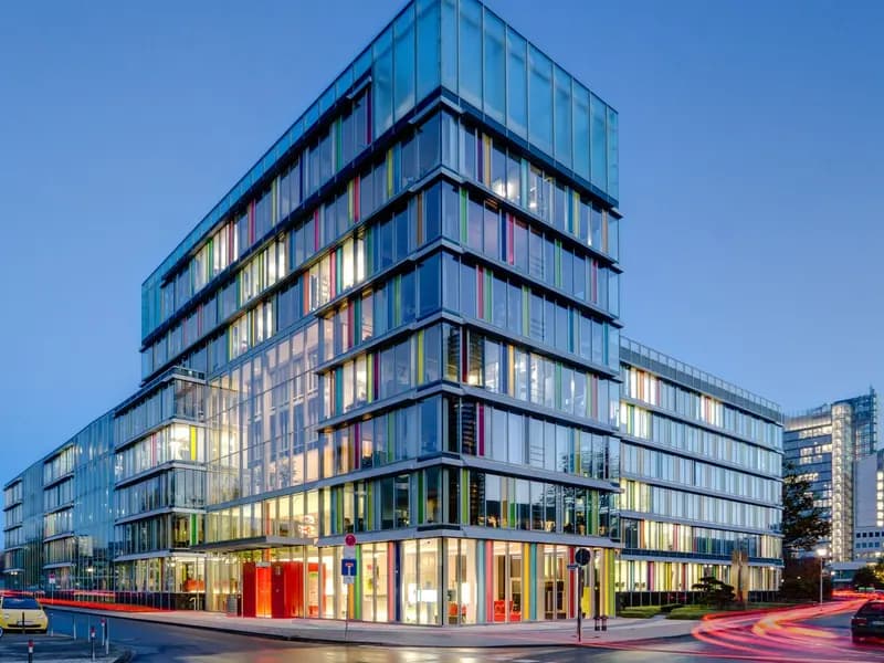 A modern glass office building lit at dusk