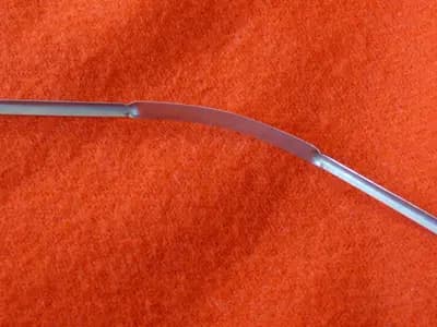 A stainless steel tongue scraper, the curved blade drawn from the back of the tongue forwards
