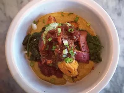 A bowl of creamy red lentil dal with golden tadka-infused oil and fresh cilantro on top, served with rice