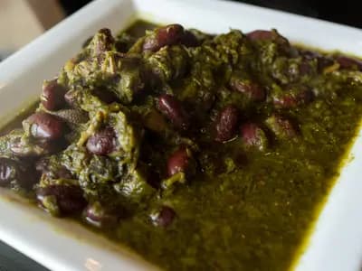 Bowl of fragrant Persian ghormeh sabzi stew with tender meat, kidney beans, and fresh herbs served over golden saffron rice