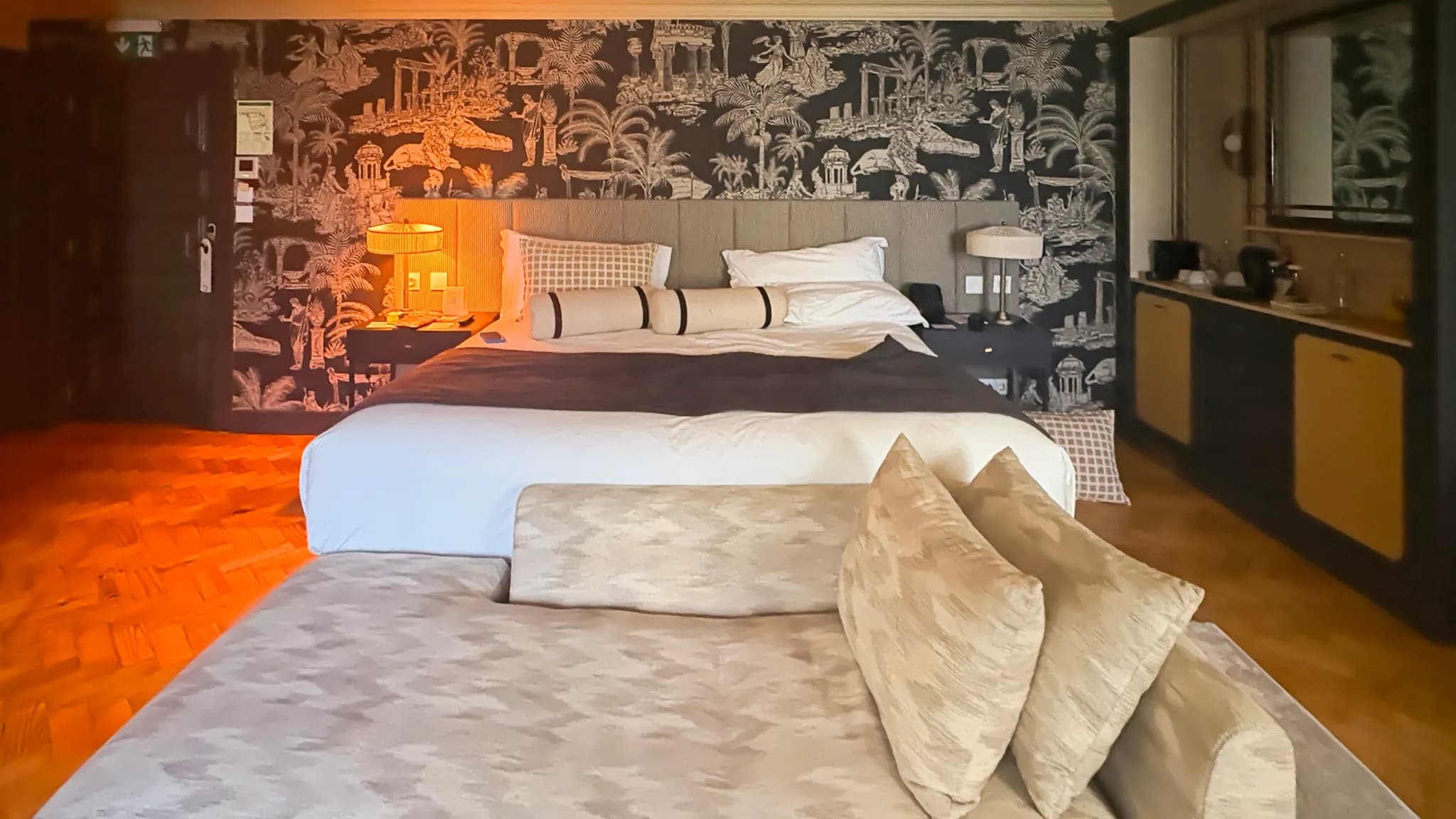 A rich, layered interior with chocolate brown walls, jewel-tone textiles, and mixed vintage and modern furnishings