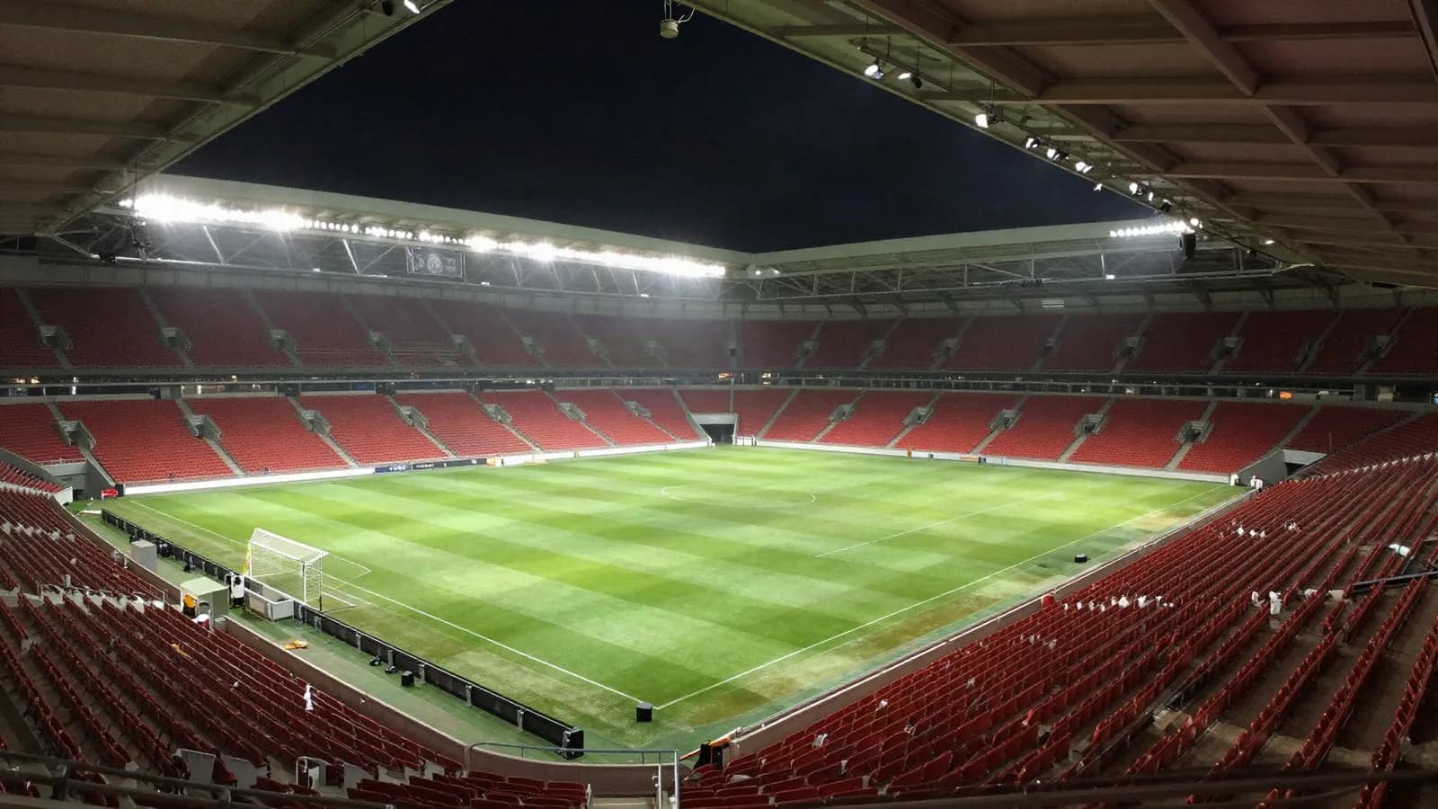 Editorial illustration of an empty floodlit football stadium at night