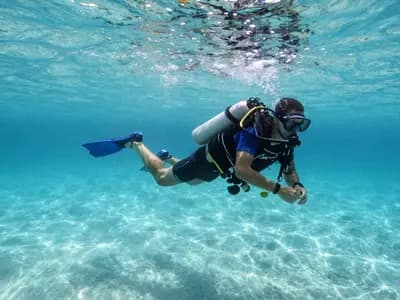 A scuba diver holding a safety stop in shallow turquoise water