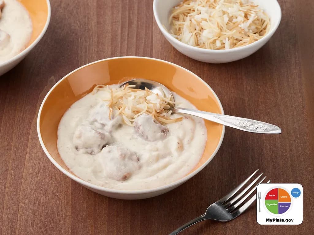 Lamb in a pale yoghurt sauce served over rice with toasted nuts