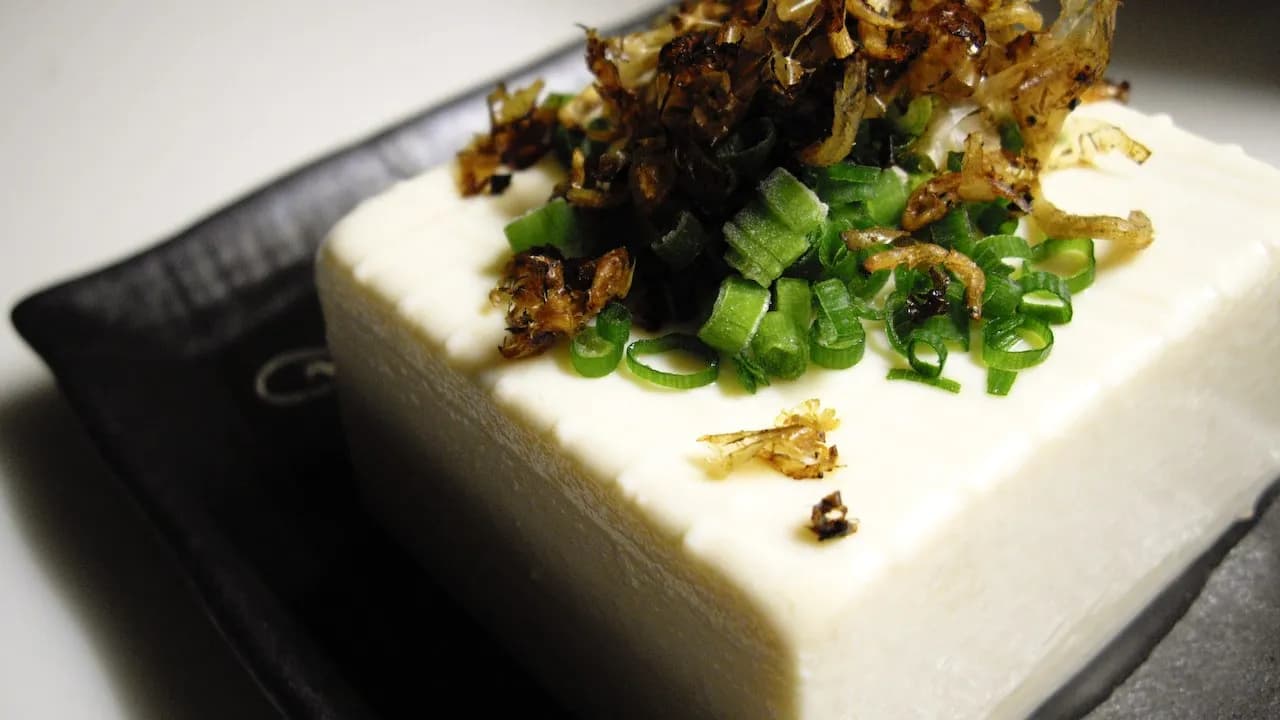 Hiyayakko, a block of cold silken tofu topped with sliced spring onion and fried aromatics, which is the Japanese version of this dish
