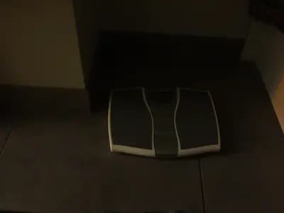 A bathroom scale on a tiled floor photographed in soft natural light