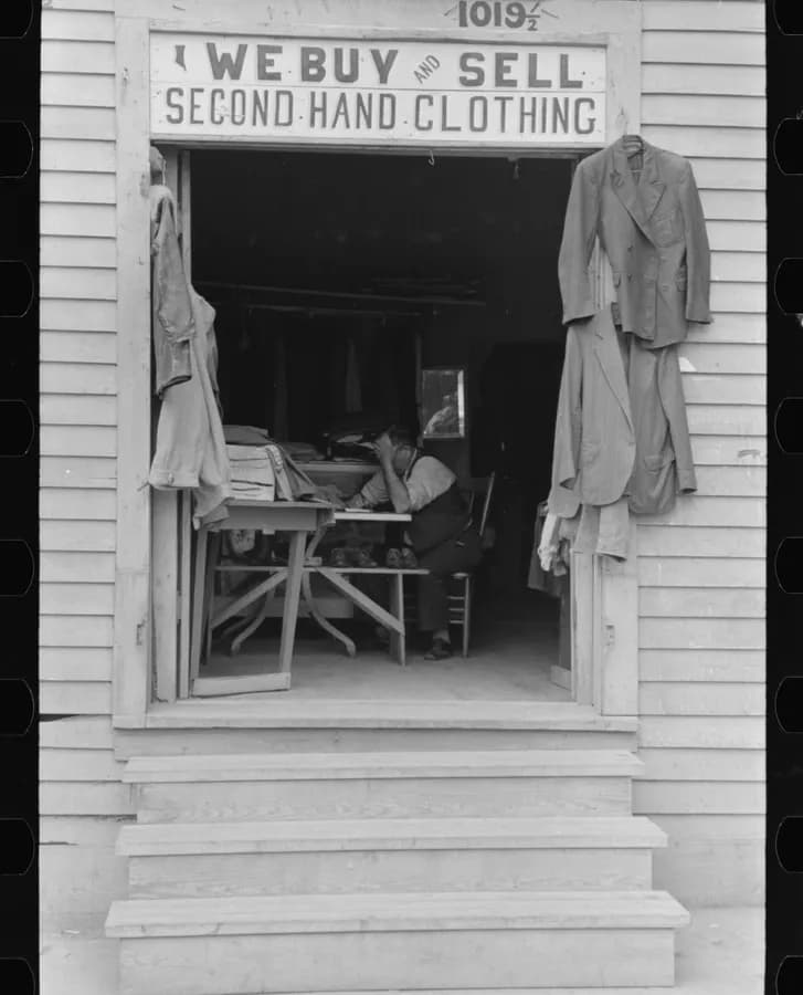 Organized racks of secondhand and vintage clothing in warm-lit boutique setting