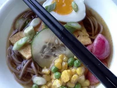 A bowl of cold buckwheat noodles in a pale sesame dressing with cucumber