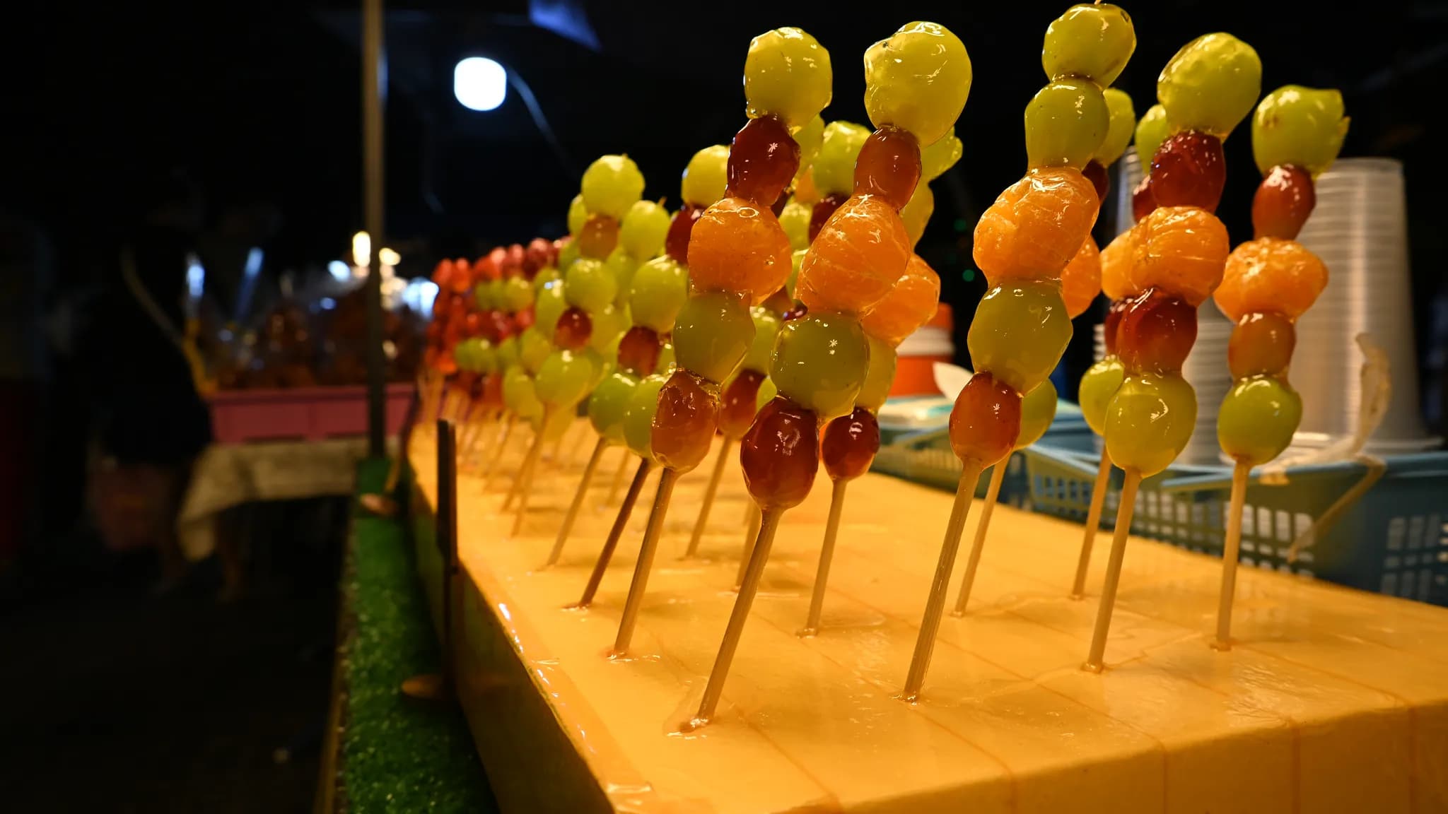 A row of glossy, sugar-glazed candied strawberry skewers with a hard, cracked candy shell, tanghulu style