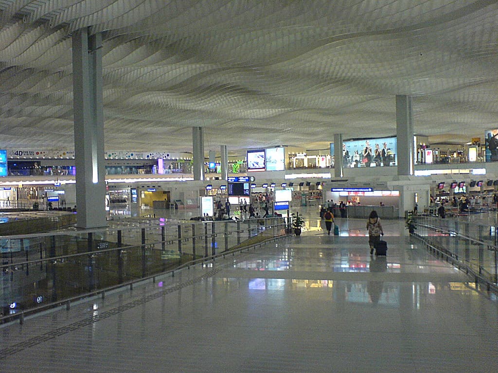 A traveler at a European airport biometric border control kiosk with a departure board in the background