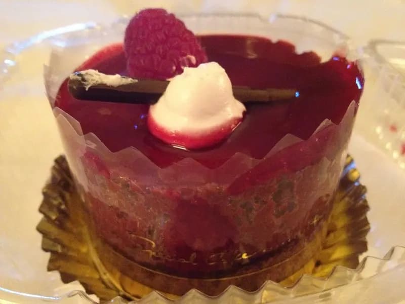 A tall glass of silky dark chocolate mousse topped with fresh raspberries and cocoa powder