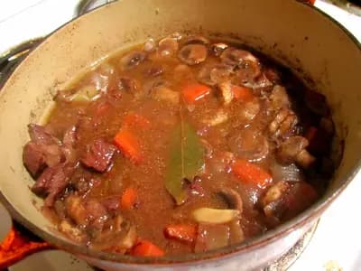 A bowl of tender mushroom bourguignon with glazed pearl onions and carrots in deep red wine sauce
