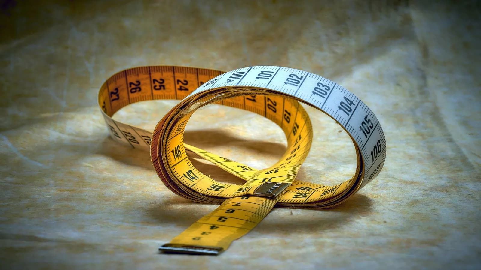A tailor's cloth tape measure coiled on a table, marked in centimetres and inches