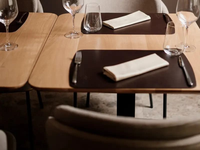 Tables laid with wine glasses, cutlery and folded napkins in a restaurant dining room