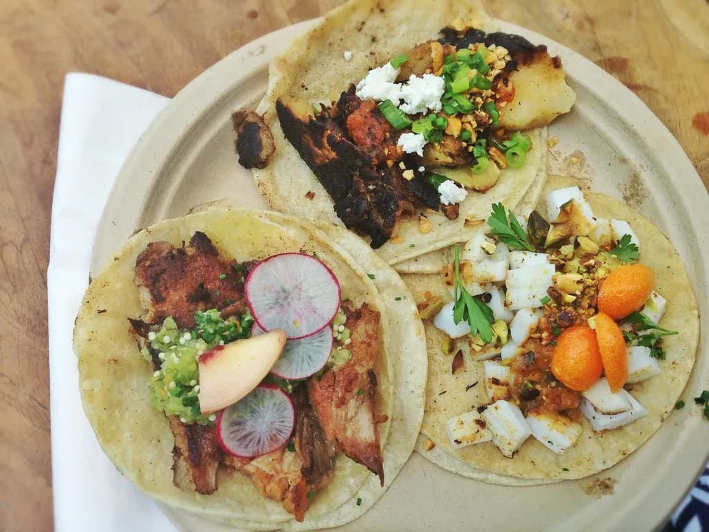 Corn tortillas filled with spiced chicken, herbs and a pale sesame sauce