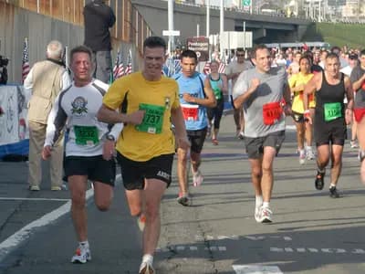 A runner in athletic gear on an outdoor track during early morning training with a heart rate monitor visible